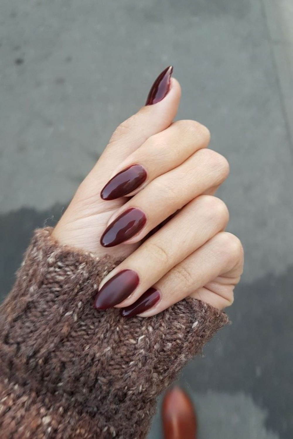 dark burgundy red nail polish, on acrylic nail shapes, worn by a